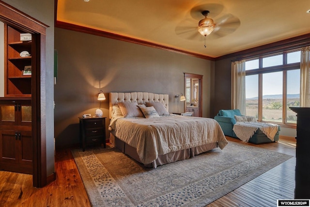 bedroom with ceiling fan, ornamental molding, dark hardwood / wood-style flooring, and a mountain view