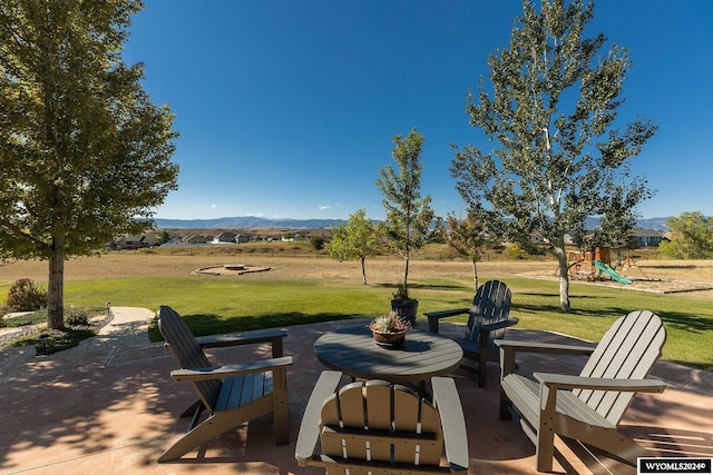 view of patio featuring a playground and a mountain view