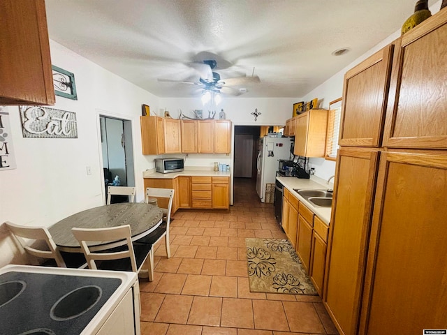 kitchen featuring light tile patterned flooring, sink, range, white fridge, and ceiling fan