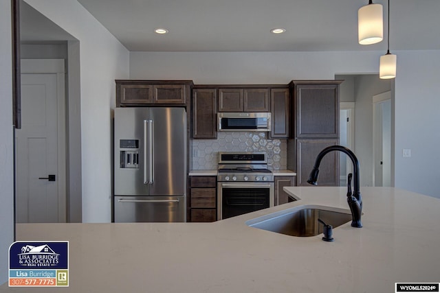 kitchen featuring pendant lighting, sink, decorative backsplash, stainless steel appliances, and dark brown cabinetry