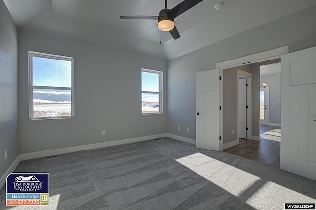 unfurnished bedroom with dark colored carpet, vaulted ceiling, and ceiling fan