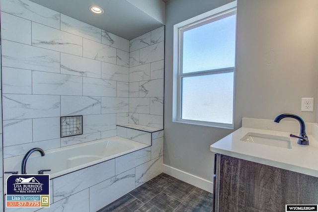 bathroom with a wealth of natural light, tiled bath, and vanity