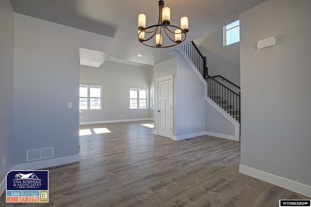 unfurnished dining area featuring an inviting chandelier and hardwood / wood-style floors