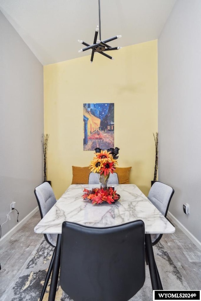 dining room featuring vaulted ceiling, a chandelier, and hardwood / wood-style flooring