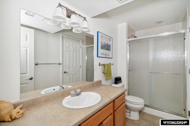 bathroom with tile patterned floors, a shower with shower door, vanity, and toilet