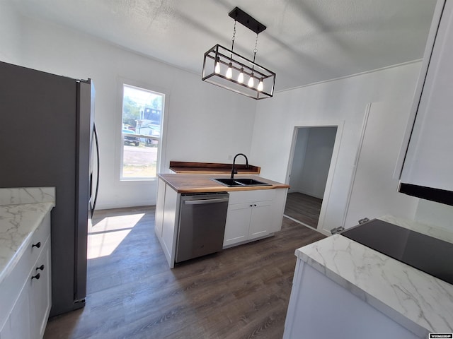 kitchen with pendant lighting, appliances with stainless steel finishes, wooden counters, white cabinetry, and sink