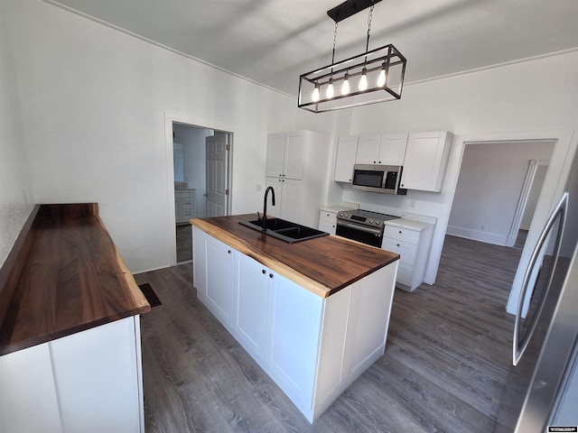 kitchen featuring sink, a center island with sink, wood counters, and appliances with stainless steel finishes