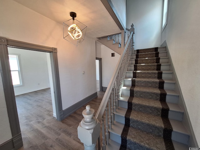 stairs featuring hardwood / wood-style flooring and a notable chandelier