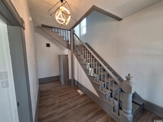 stairs featuring wood-type flooring and a notable chandelier