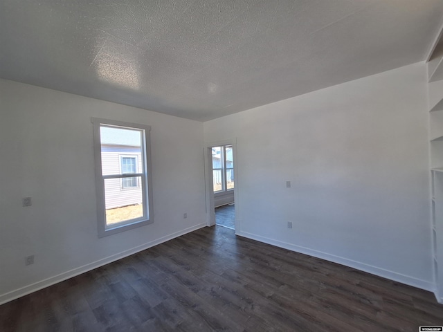 unfurnished room featuring a textured ceiling and dark hardwood / wood-style flooring