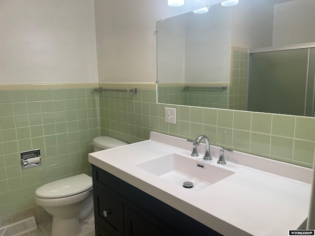 bathroom featuring vanity, a shower with shower door, tile patterned floors, tile walls, and toilet