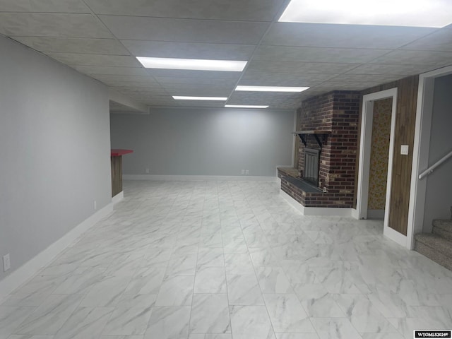 basement with a drop ceiling and a fireplace