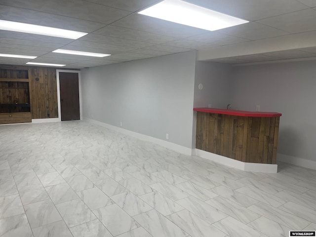 basement with a drop ceiling and indoor bar