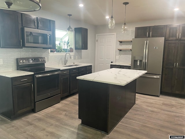 kitchen featuring light stone counters, a center island, sink, light hardwood / wood-style flooring, and appliances with stainless steel finishes