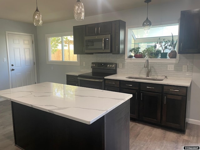 kitchen featuring light hardwood / wood-style floors, black range with electric stovetop, tasteful backsplash, decorative light fixtures, and sink