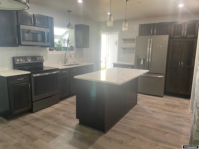 kitchen featuring appliances with stainless steel finishes, a center island, sink, and light hardwood / wood-style flooring