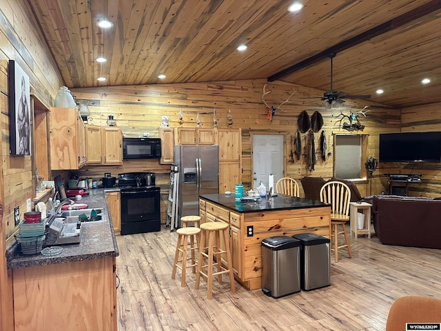 kitchen with lofted ceiling with beams, black appliances, a center island, light hardwood / wood-style flooring, and ceiling fan