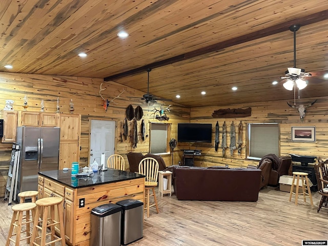 kitchen with lofted ceiling with beams, stainless steel refrigerator with ice dispenser, a kitchen island, light hardwood / wood-style flooring, and wooden ceiling