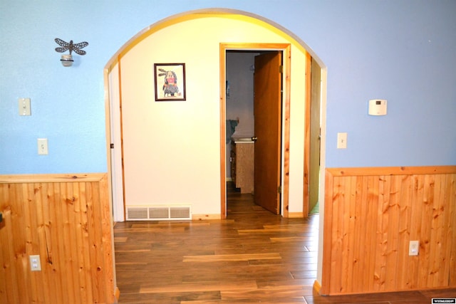 corridor featuring wooden walls and dark hardwood / wood-style flooring