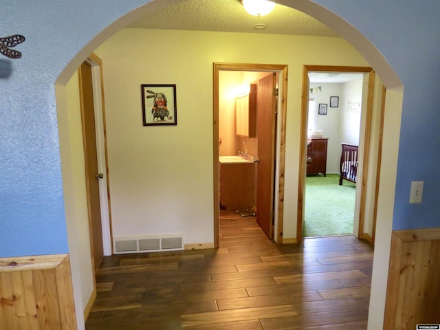 hallway with a textured ceiling and dark wood-type flooring