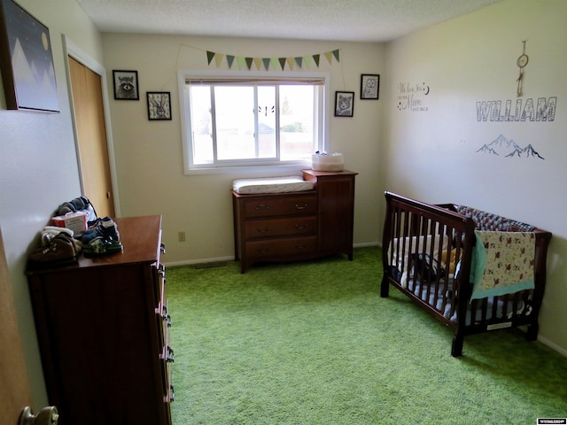 carpeted bedroom with a crib and a textured ceiling