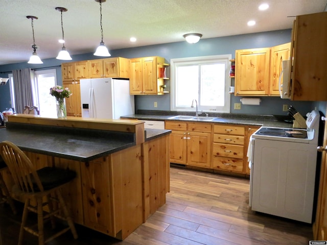 kitchen featuring light wood-type flooring, sink, white appliances, and a wealth of natural light