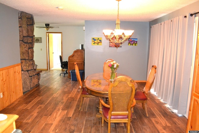 dining area with wooden walls, ceiling fan with notable chandelier, dark wood-type flooring, and a textured ceiling