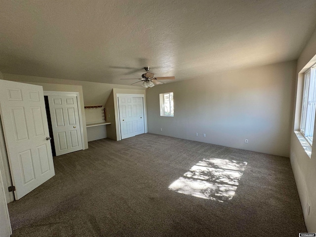 interior space featuring dark colored carpet, a textured ceiling, and ceiling fan