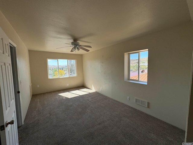 unfurnished room with ceiling fan and carpet