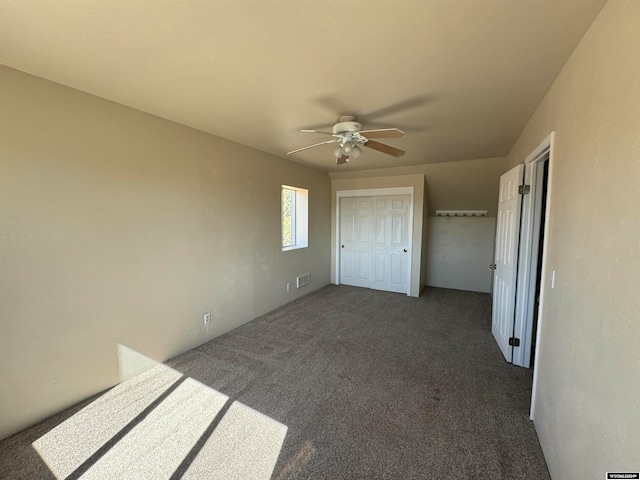 unfurnished bedroom featuring ceiling fan, a closet, and dark colored carpet