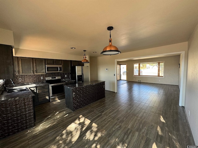 kitchen featuring tasteful backsplash, sink, stainless steel appliances, hanging light fixtures, and a center island