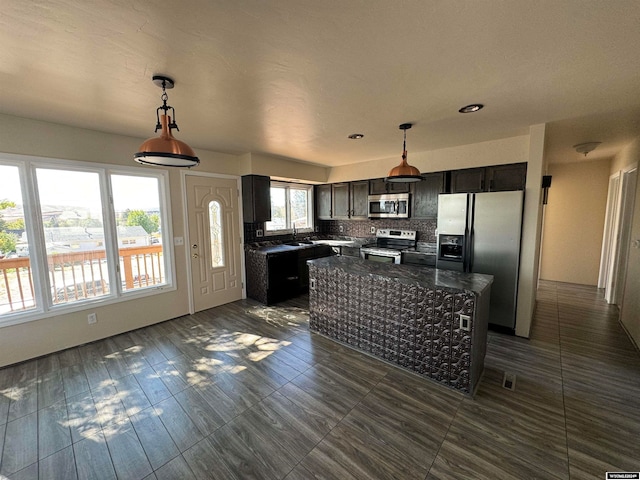 kitchen with decorative light fixtures, stainless steel appliances, a center island, and a wealth of natural light