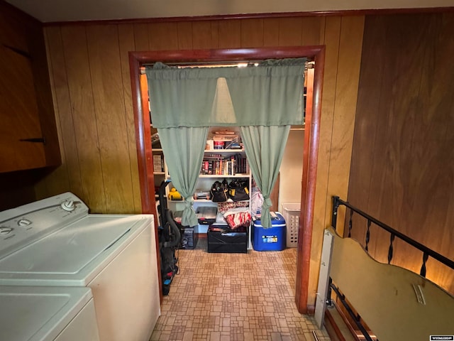 washroom with separate washer and dryer, wooden walls, and cabinets