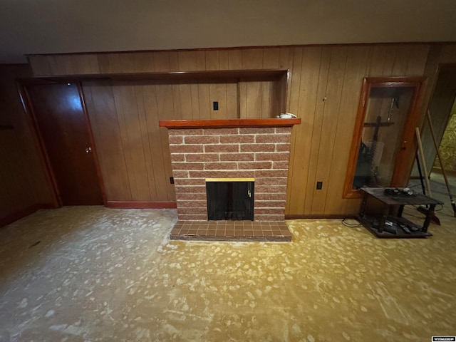 unfurnished living room featuring wood walls and a brick fireplace