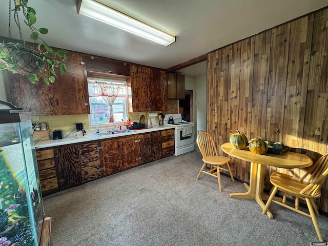 kitchen with electric range, wood walls, sink, and light carpet