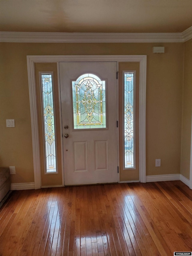 foyer with light wood-type flooring, crown molding, and a wealth of natural light