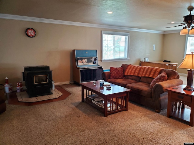 carpeted living room with ceiling fan, plenty of natural light, ornamental molding, and a wood stove