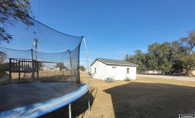 exterior space with a trampoline, an outdoor structure, and a yard