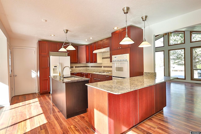 kitchen featuring pendant lighting, sink, white appliances, dark hardwood / wood-style floors, and light stone countertops