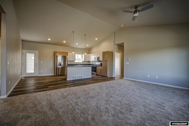 kitchen with light brown cabinetry, dark colored carpet, a center island, appliances with stainless steel finishes, and pendant lighting