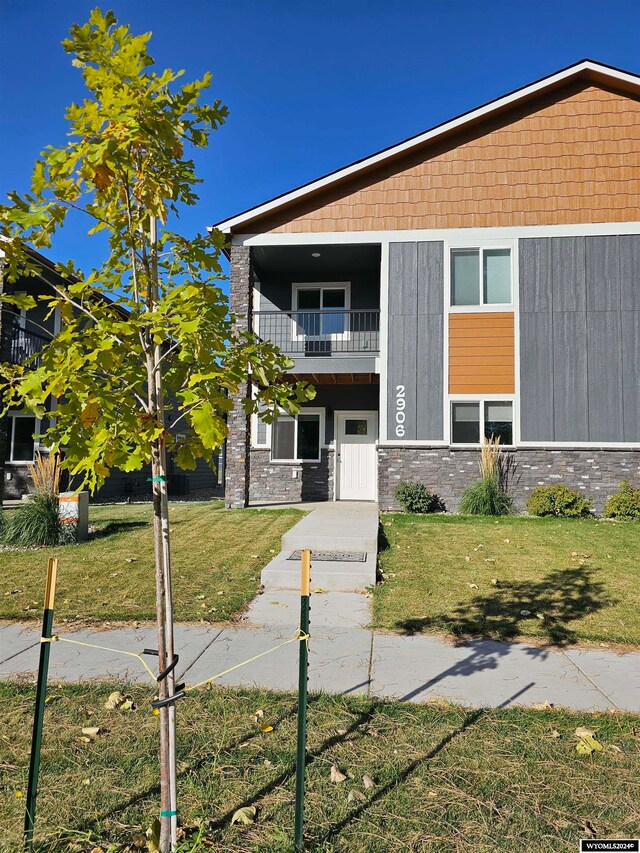 view of front facade with a front yard and a balcony