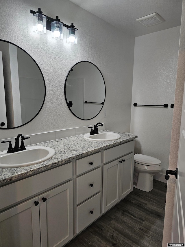 bathroom with toilet, vanity, and wood-type flooring