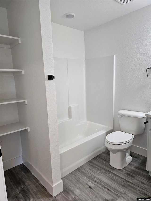 bathroom featuring bathing tub / shower combination, toilet, and wood-type flooring