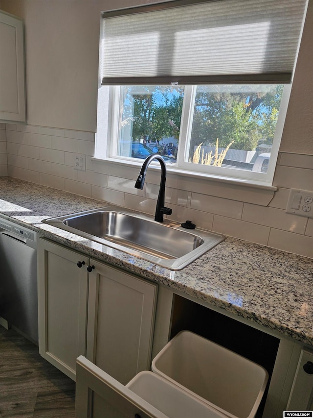 kitchen featuring light stone counters, backsplash, sink, and stainless steel dishwasher