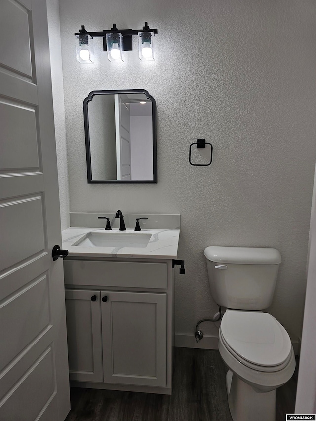 bathroom with hardwood / wood-style floors, toilet, and vanity