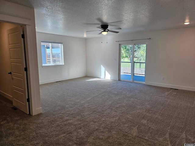 spare room with ceiling fan, dark carpet, and a textured ceiling