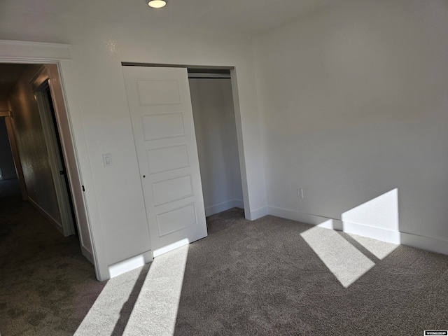 unfurnished bedroom with a closet and dark carpet