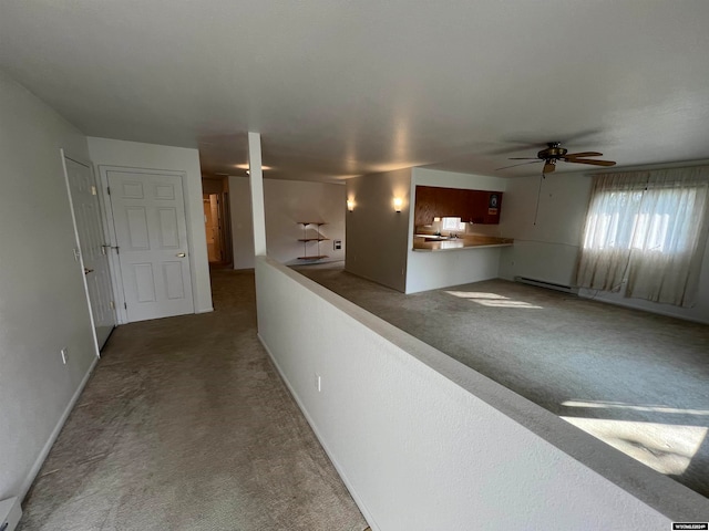 interior space with ceiling fan, a baseboard heating unit, and carpet