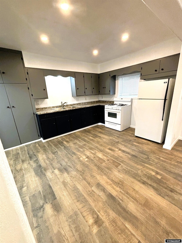 kitchen featuring white appliances, sink, and wood-type flooring