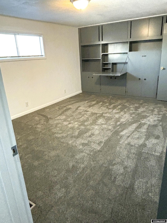 unfurnished bedroom with dark colored carpet and a textured ceiling